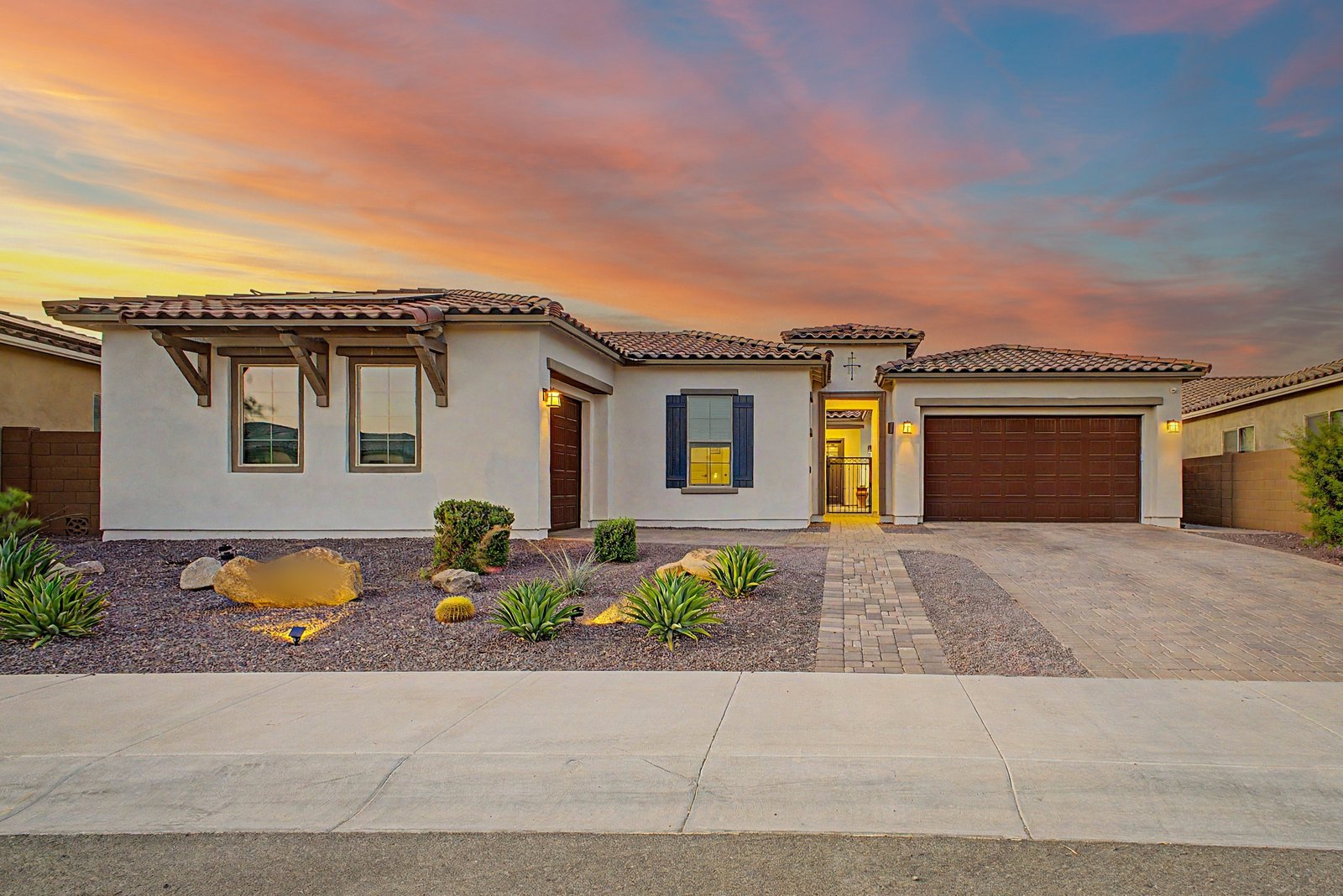 Single-story Arizona home at dusk with warm windows and a pink and blue sky